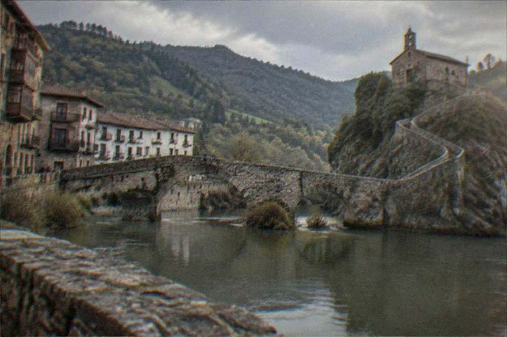 A medieval stone hermitage on a rocky islet connected by a long winding causeway staircase