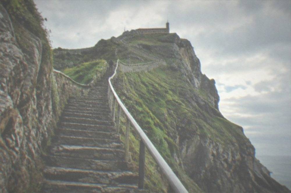 The steep rock-cut staircase with handrail climbing toward the hermitage of San Juan at Gaztelugatxe