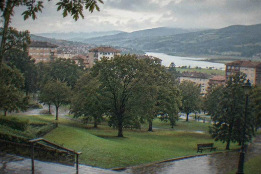 Green rolling hills of the Basque Country under a partly cloudy sky with the Urdaibai estuary in the distance