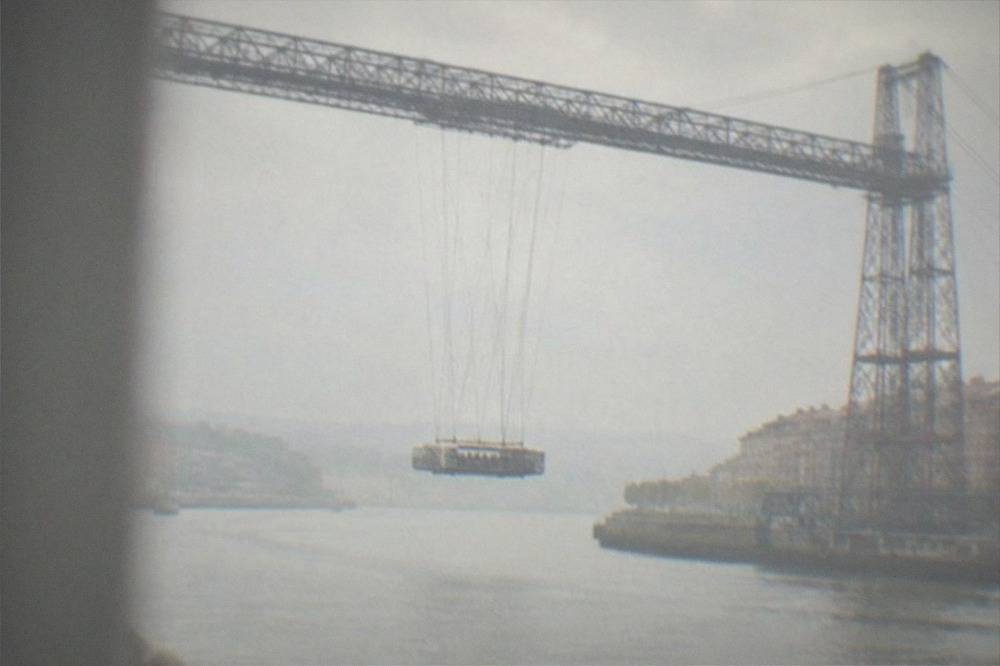 The suspended gondola of the Vizcaya Bridge carrying passengers across the estuary below the iron structure