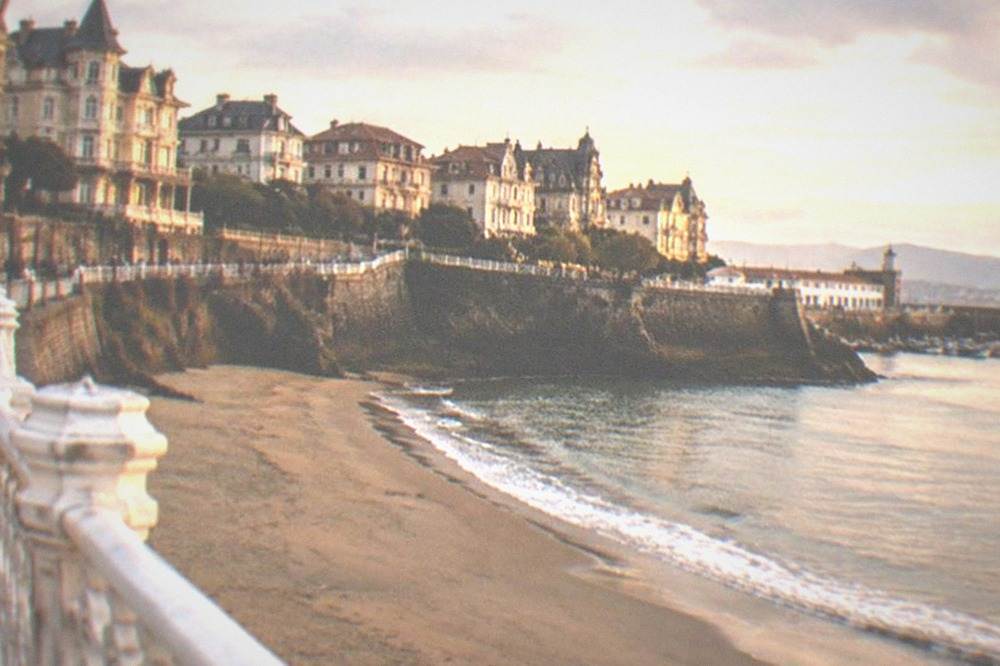 A sandy beach in Getxo with gentle waves and a promenade lined with grand old buildings