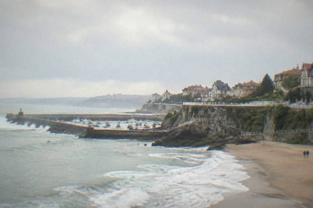 Waves breaking against a coastal breakwater under an overcast Atlantic sky