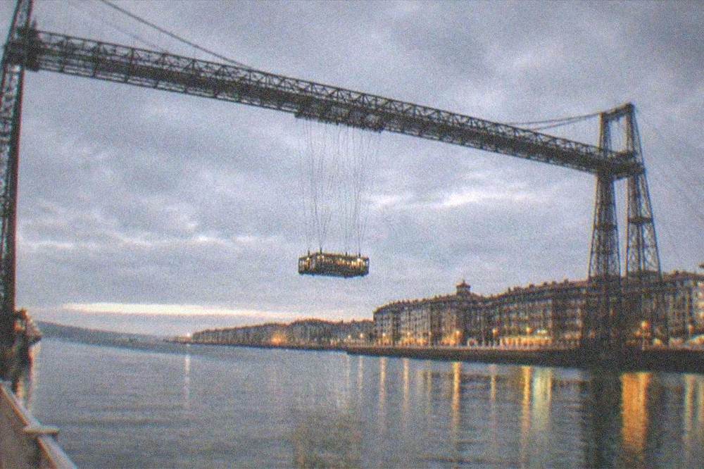 An evening view of the illuminated Vizcaya Bridge reflected in the estuary water