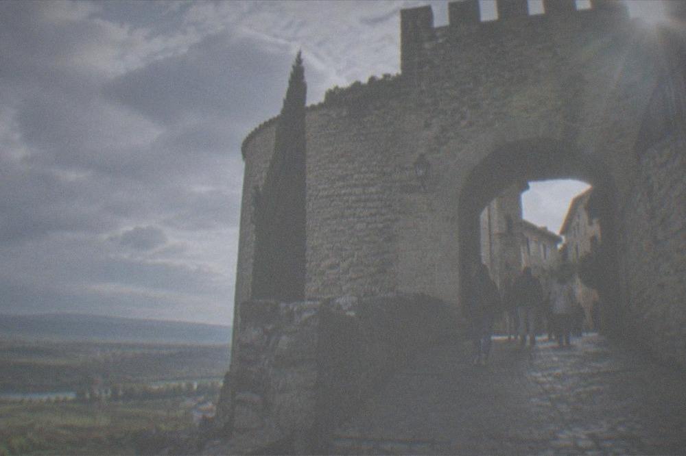 Stone gate and fortified wall of Laguardia village with visitors walking through on a sunny day