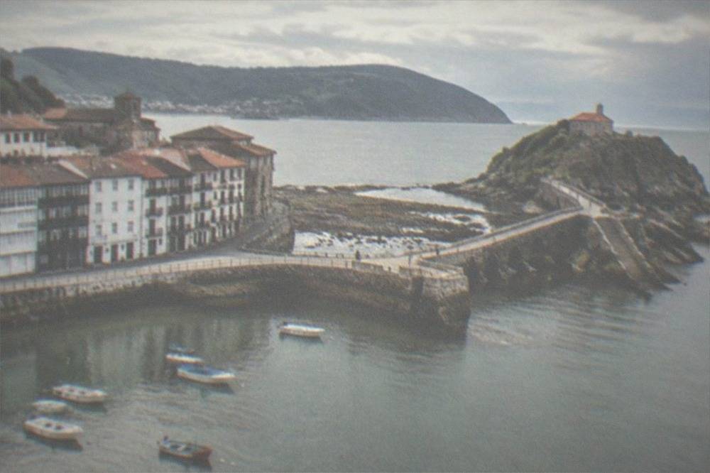 A stone causeway and steps leading to a small hermitage chapel on a rocky islet in the sea