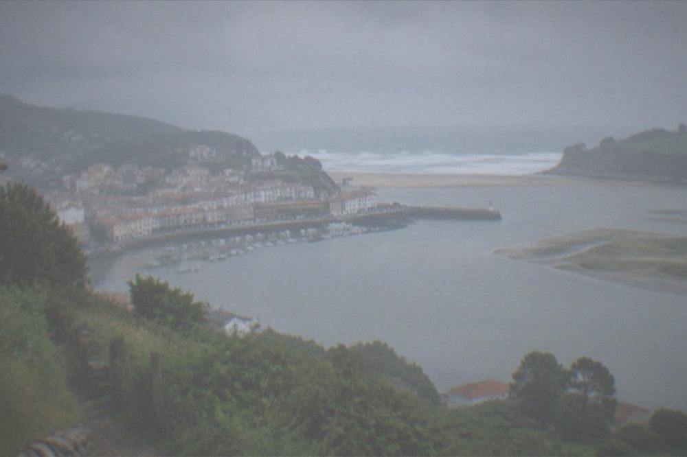View from a hillside path over the Urdaibai estuary with green slopes and tidal channels