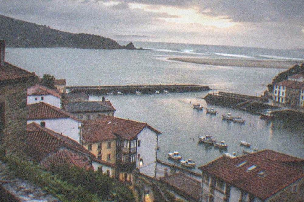 Evening light over Mundaka village rooftops with the estuary calm in the background