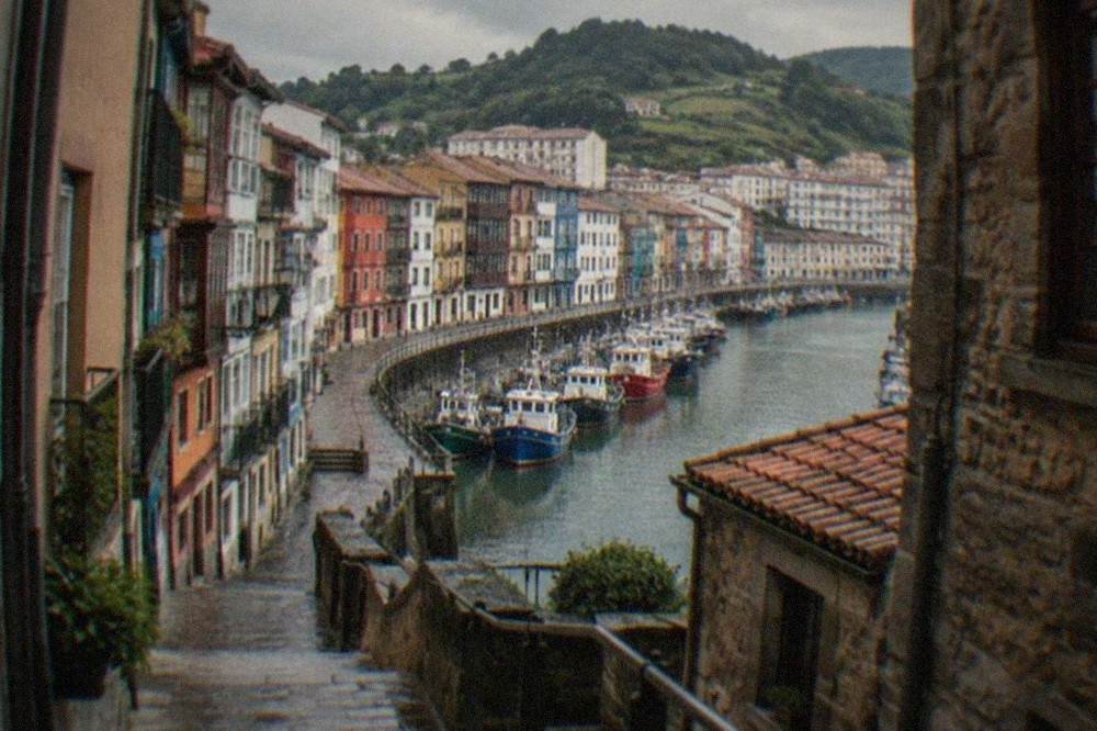 Steep narrow street of old stone and painted houses rising from a Basque harbour toward the town above