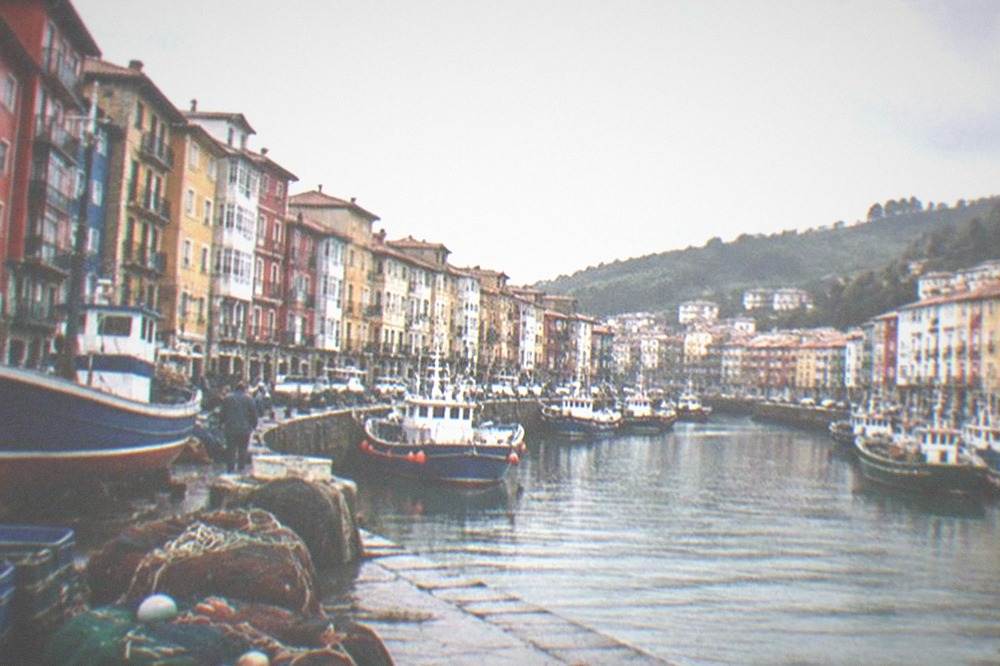 Wooden fishing boats and nets along a stone quay in a small Basque port at midday