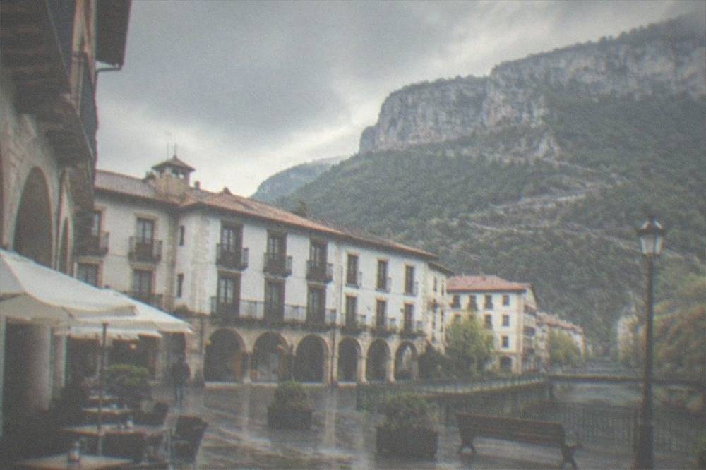 Arcaded main square of a small Basque town with café tables and mountain backdrop