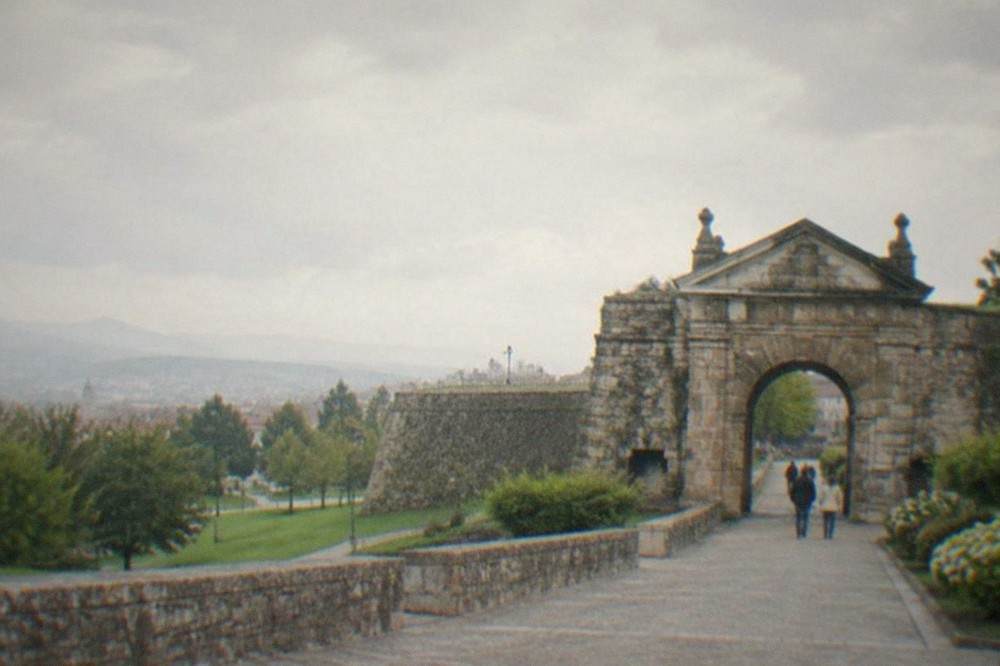 A stone gateway in Pamplona's city walls with green gardens alongside