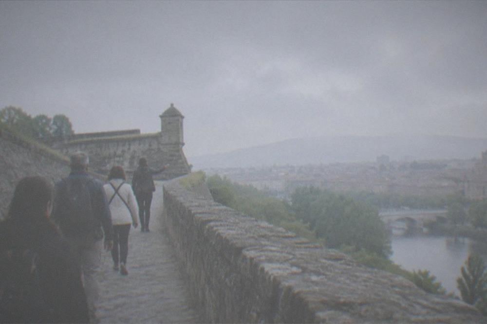 A small group of visitors walking with a guide along a stone rampart path