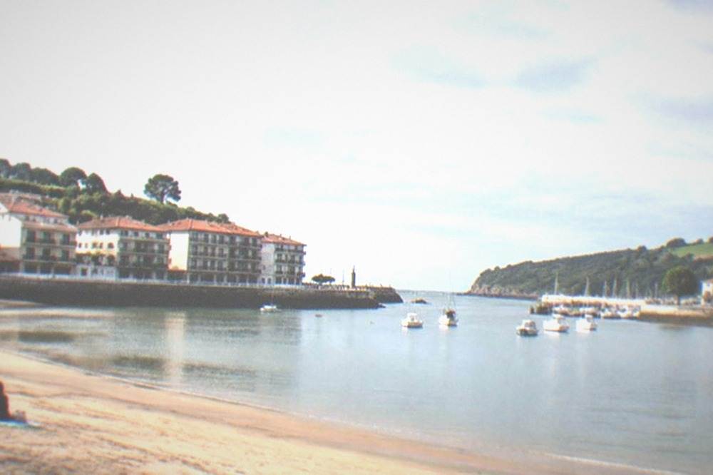 A quiet sandy beach in soft late afternoon light with few people and calm water