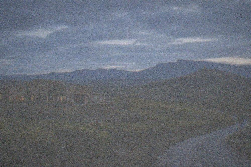 A small road curving through rolling vineyards toward a hilltop village in Rioja