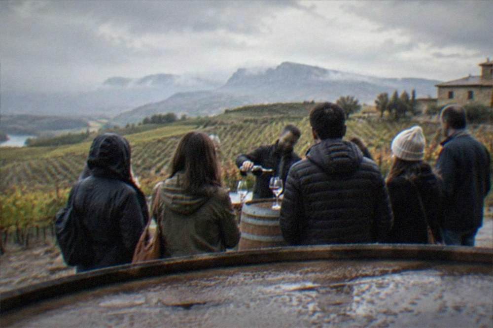 A guide pouring wine for a small group standing around barrels in a Rioja winery