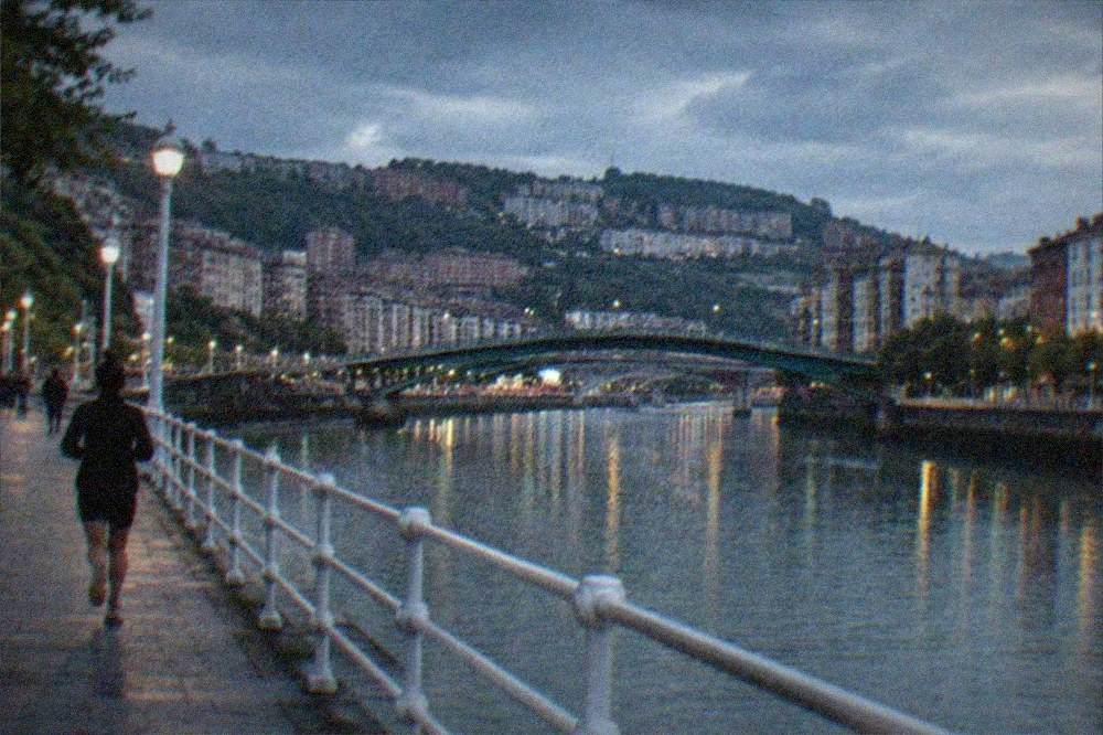 Evening light over the Bilbao estuary with bridges and buildings along the water