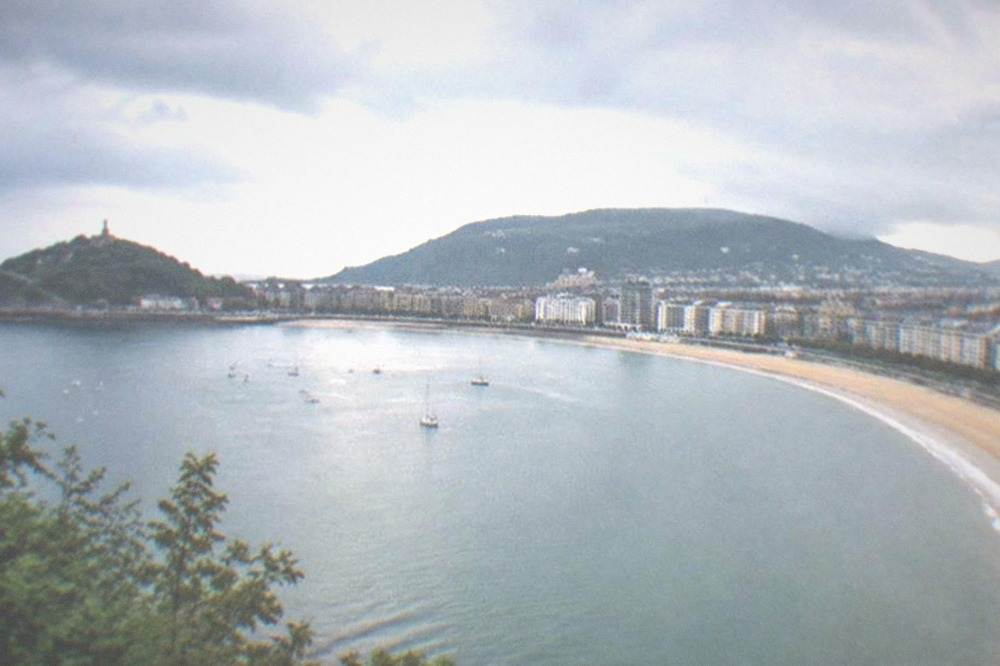 Rain clouds passing over a coastal bay with dark blue water and a distant hill