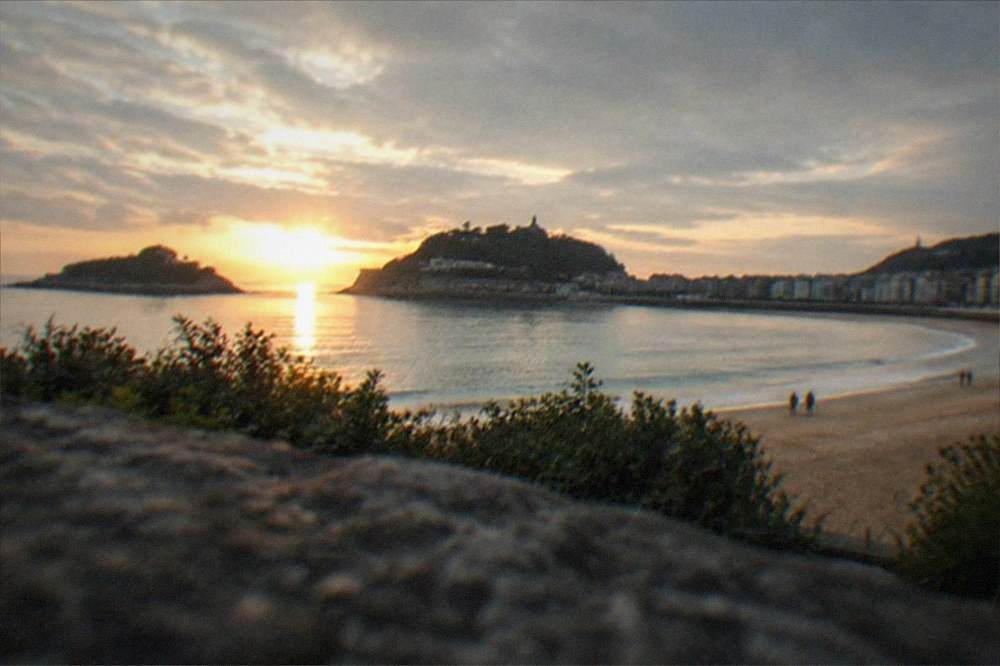 Sunset light over a coastal town with islands visible offshore and calm water