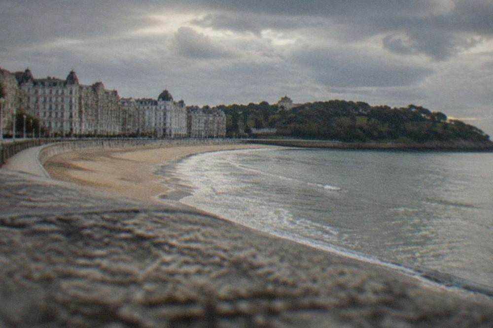 Sandy city beach in Santander with a long curved promenade and period buildings behind it