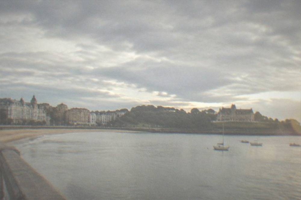 Stately peninsula palace with gardens overlooking a calm bay and small boats