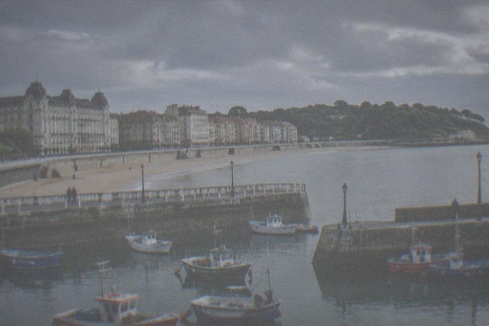 Fishing harbour with colourful wooden boats moored beside stone quays and tall townhouses