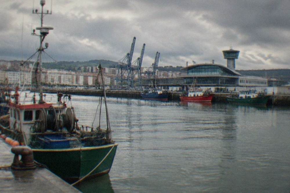 Fishing boats and port buildings along the Santurtzi waterfront on a grey Atlantic morning