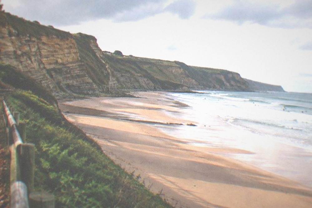 Empty beach in soft autumn light with long shadows across the sand