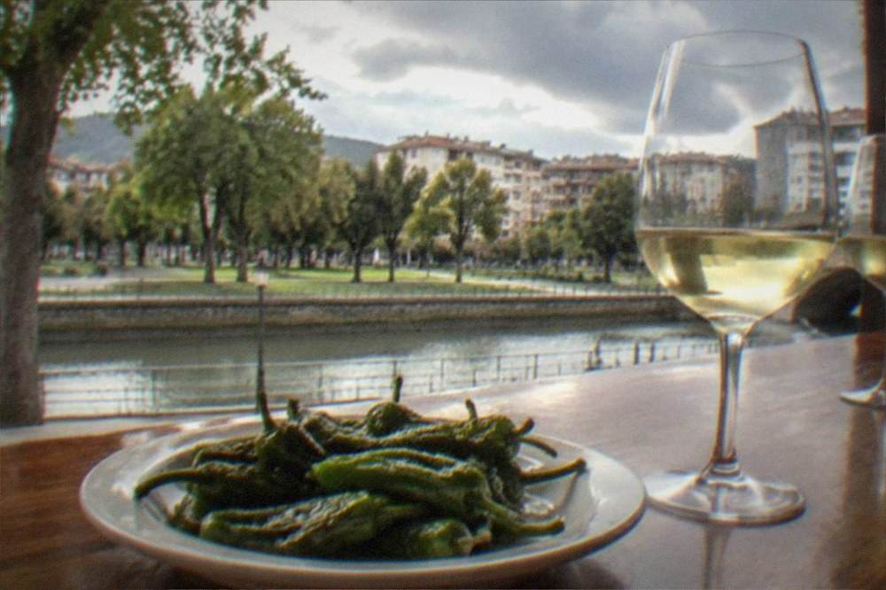 Fried green Gernika peppers and txakoli wine glasses on a bar top in a Basque taverna