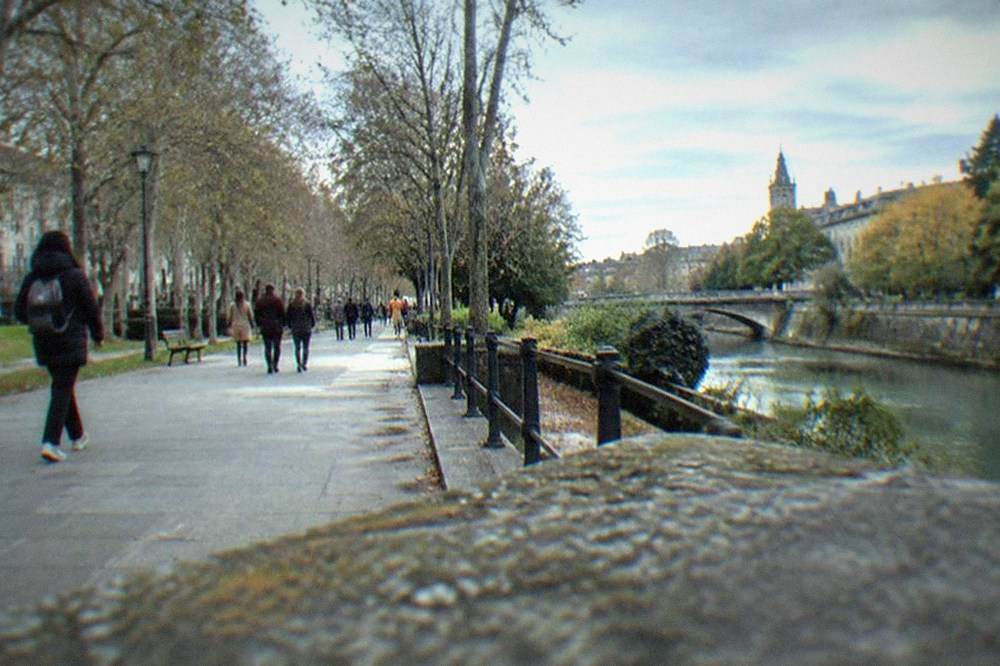 Pedestrians walking through a leafy park promenade in Vitoria-Gasteiz on a mild afternoon