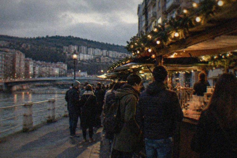 A decorated festival street bar with a small crowd ordering drinks at the counter at night