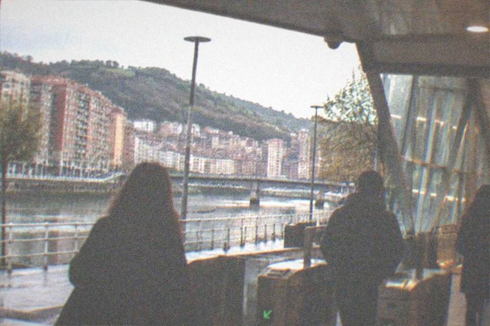 A metro station entrance with people walking through the gates in the evening