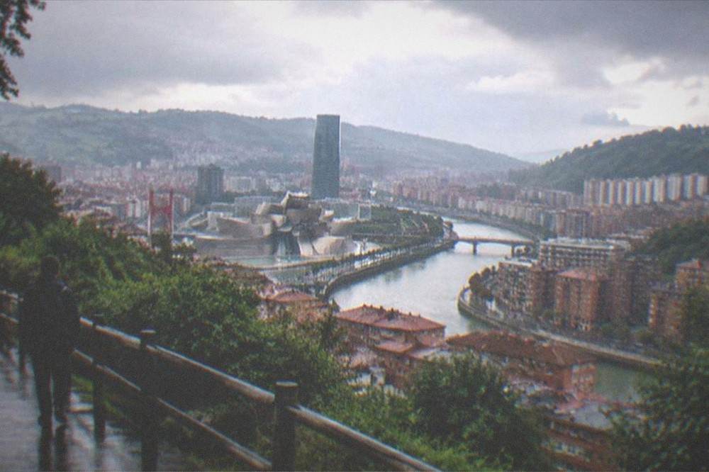 A hillside viewpoint overlooking a city skyline and river in late afternoon light