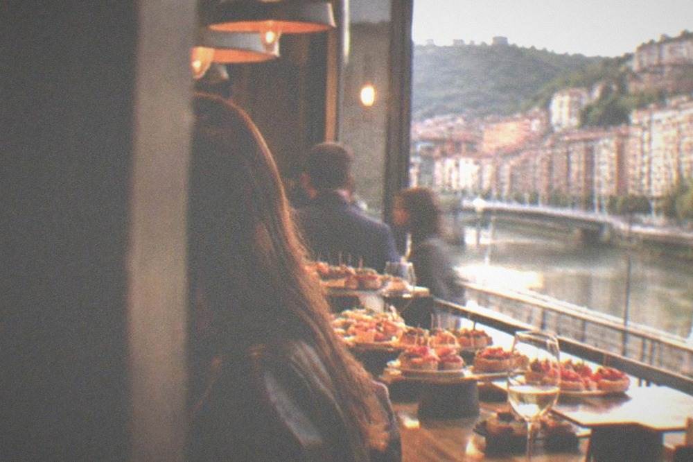 Busy pintxos bar counter in Bilbao lined with small plates and glasses of wine