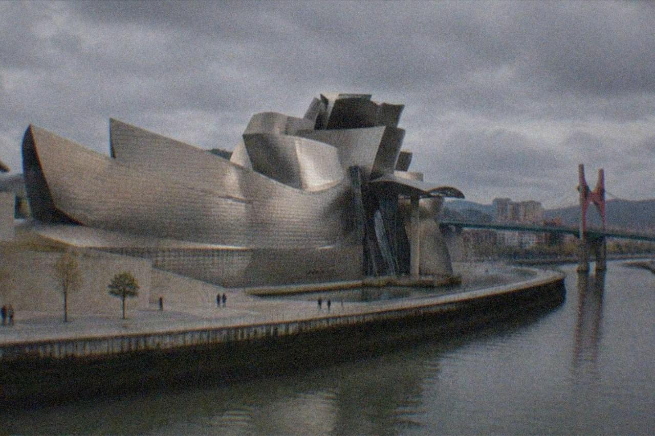 The Bilbao estuary with the Guggenheim Museum titanium curves and a pedestrian bridge in evening light