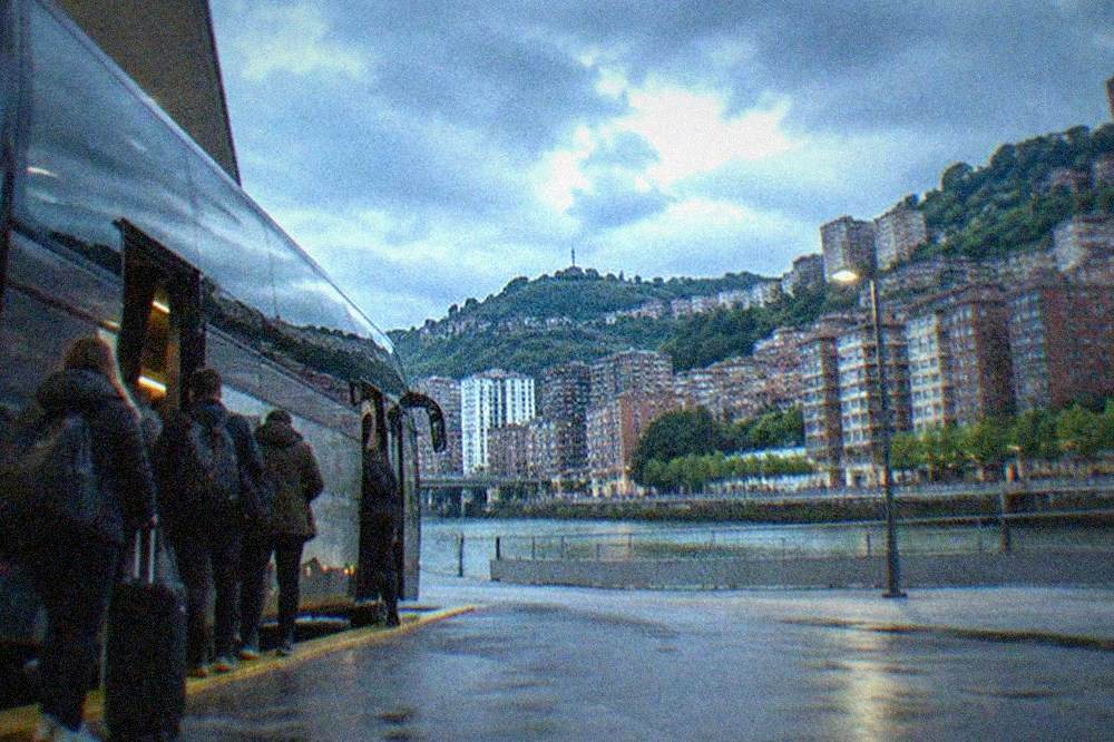 A long-distance coach parked at the Bilbao Intermodal bus station with travelers boarding