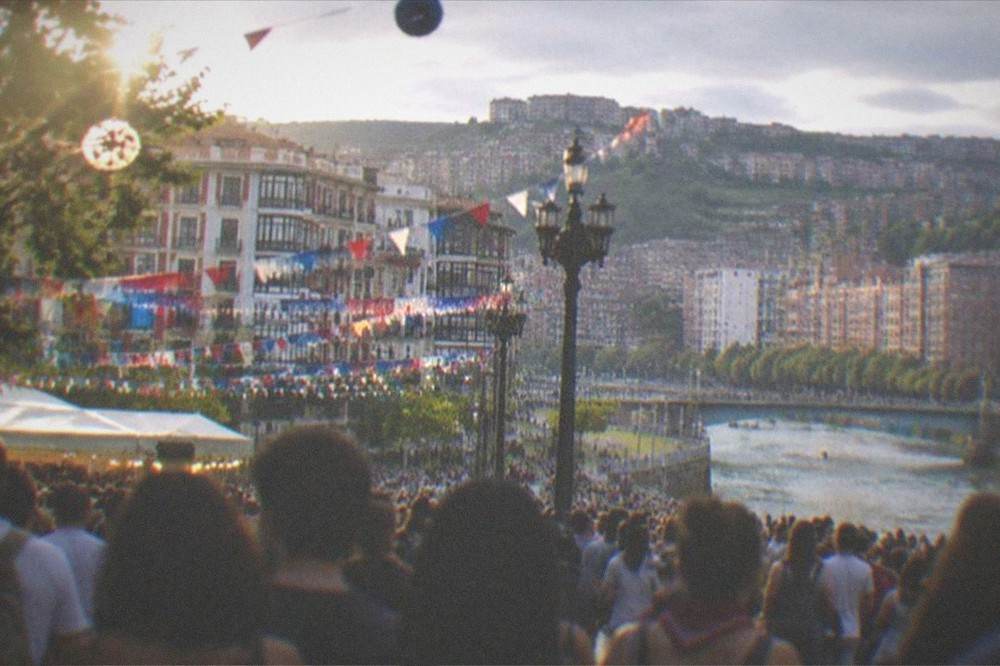 Crowds filling a Bilbao square during the Aste Nagusia festival with festive decorations overhead