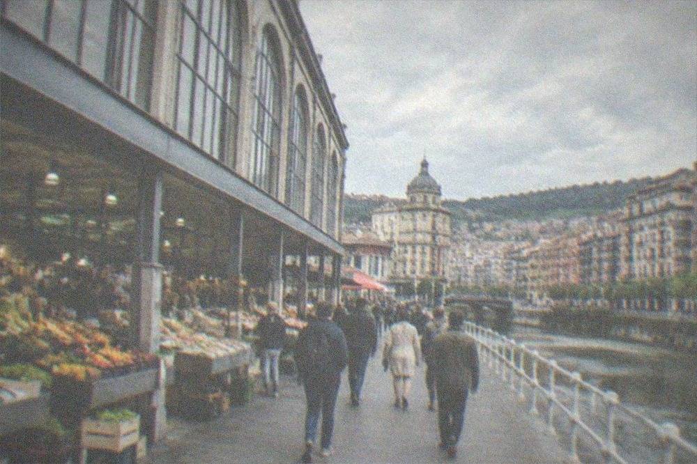 An arcaded square in Bilbao's old town with people walking between pintxos bars in the evening
