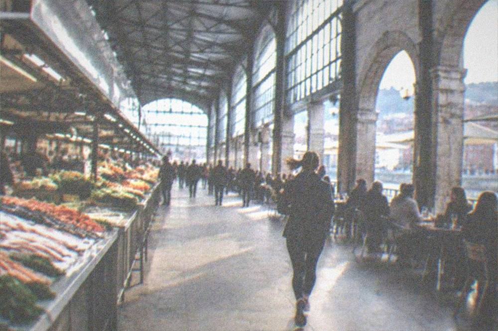 People eating and drinking at outdoor tables under arcade arches on a warm evening