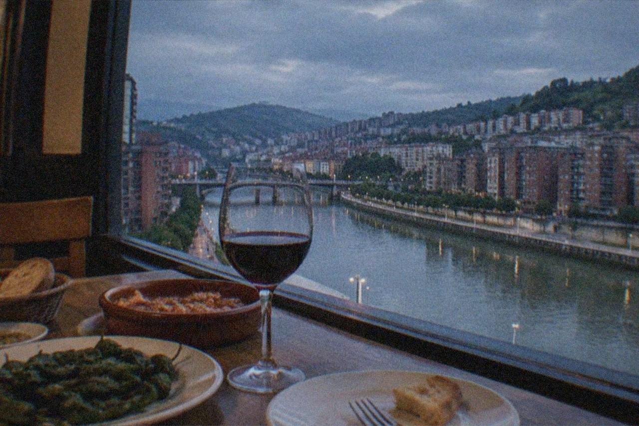 A dining table set with Basque dishes and a glass of red wine in a warm restaurant interior