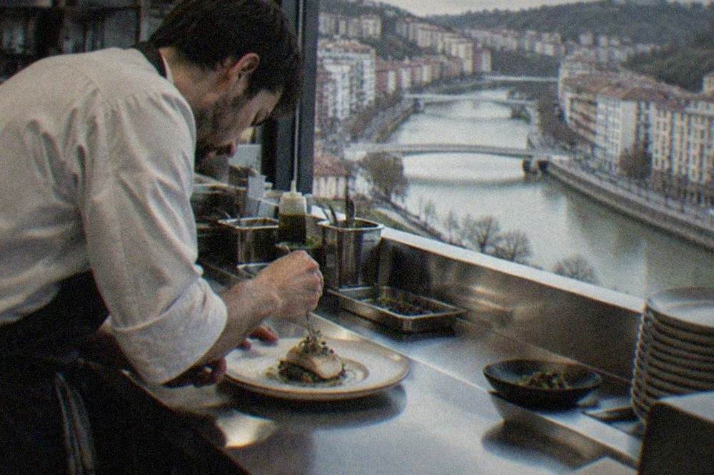 A chef plating a small modern Basque dish in a restaurant kitchen