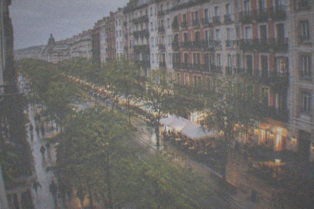 An evening street in the Ensanche district with lit restaurant terraces and people walking