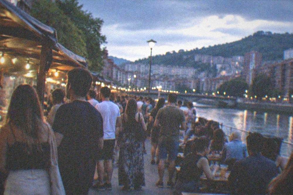A festival crowd eating at outdoor street food stalls on a summer evening