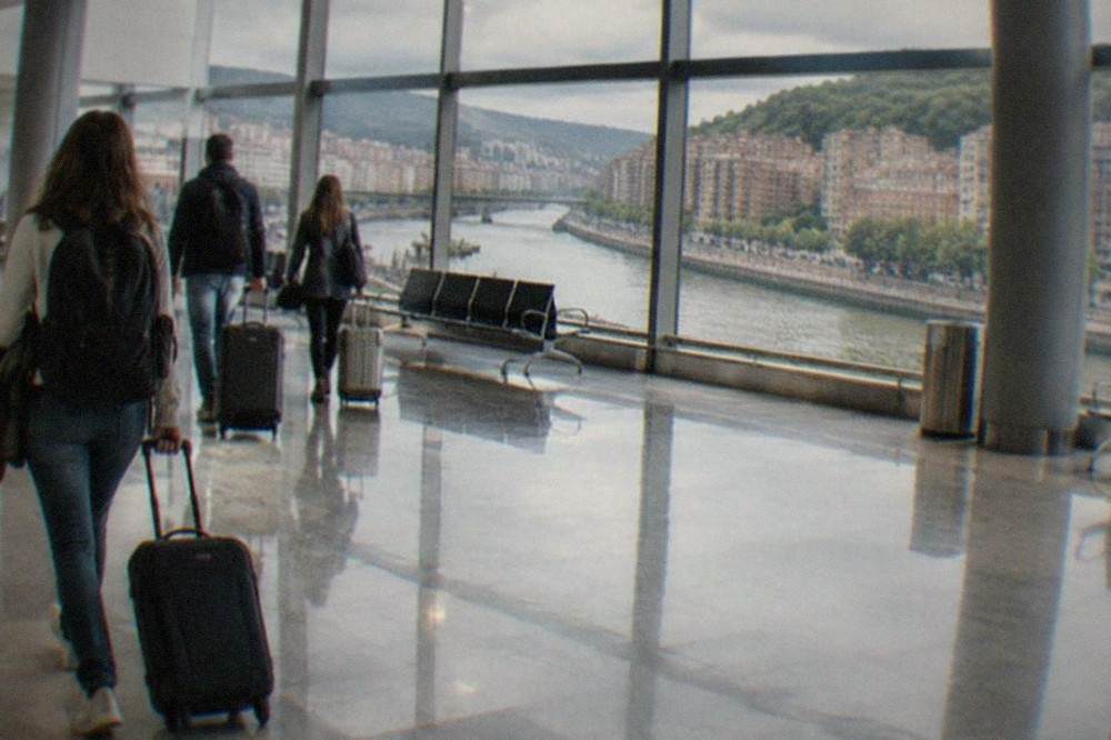 Passengers with luggage walking through the bright arrivals hall of Bilbao Airport