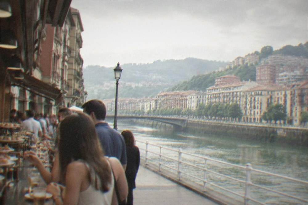 People eating pintxos and drinking at a crowded bar counter in the old town of Bilbao