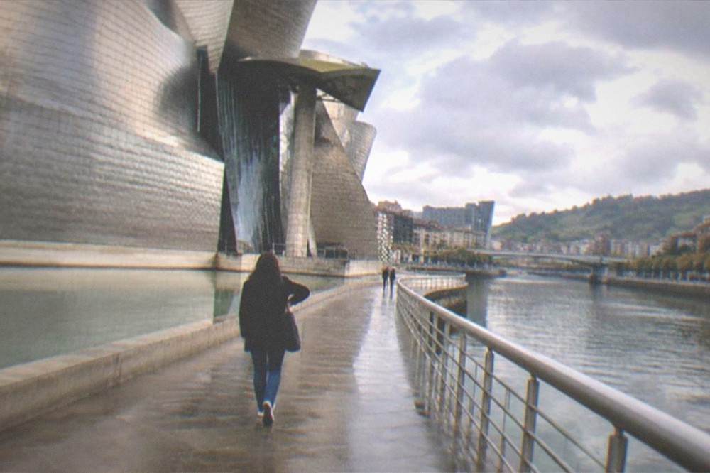 A traveller putting a wallet away while walking along the Bilbao riverside near the Guggenheim Museum