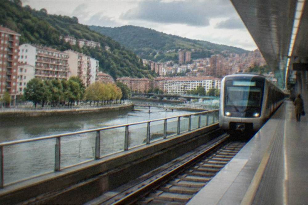 A modern Bilbao metro station platform with clean architecture and a train arriving