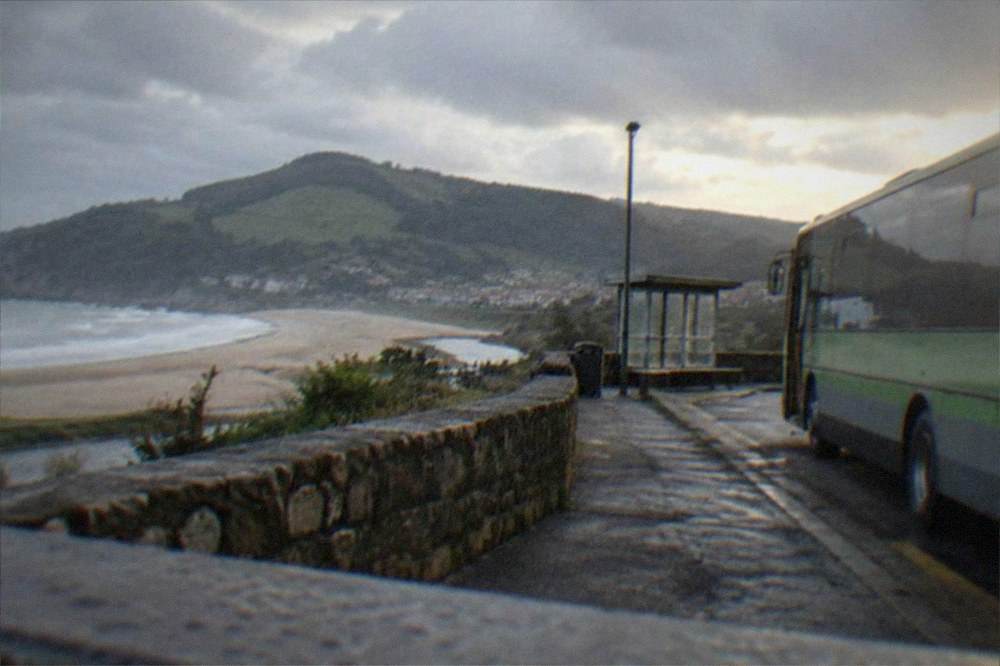 A Bizkaibus regional bus parked at a stop overlooking the Basque coastline near Bakio