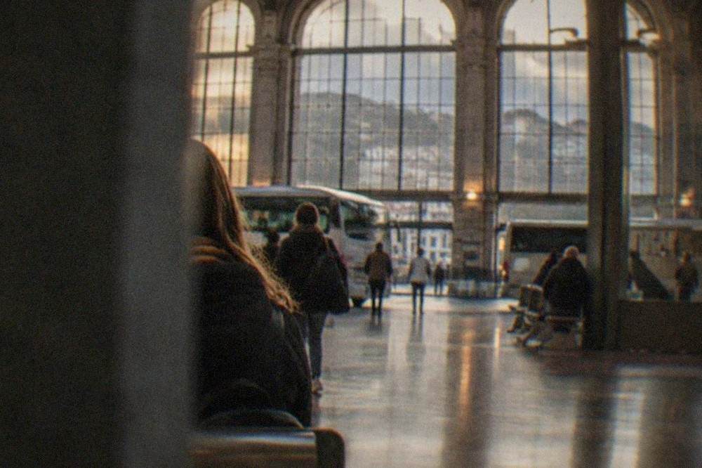 Interior of a bus interchange hall with departure boards and travellers with luggage