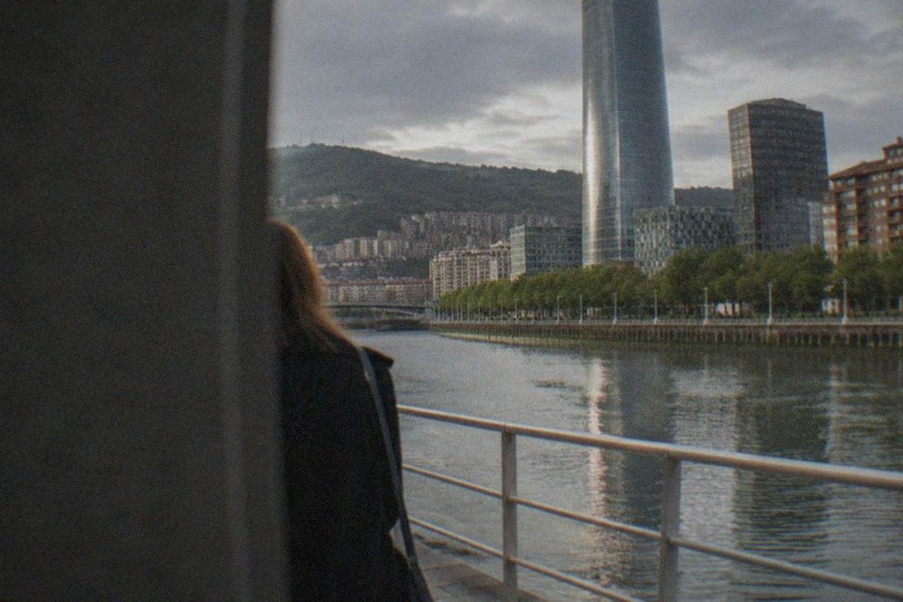 Modern office towers and the Bilbao estuary seen from across the water on a clear morning