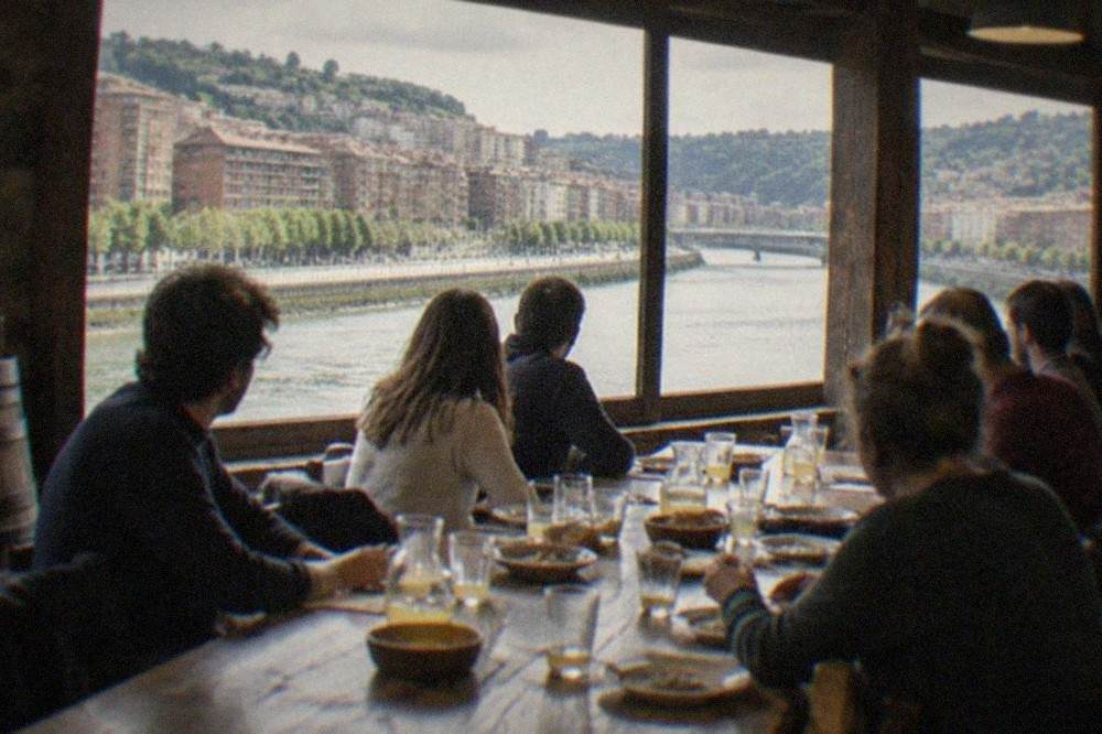 A long wooden table set for a group meal inside a rustic Basque cider house